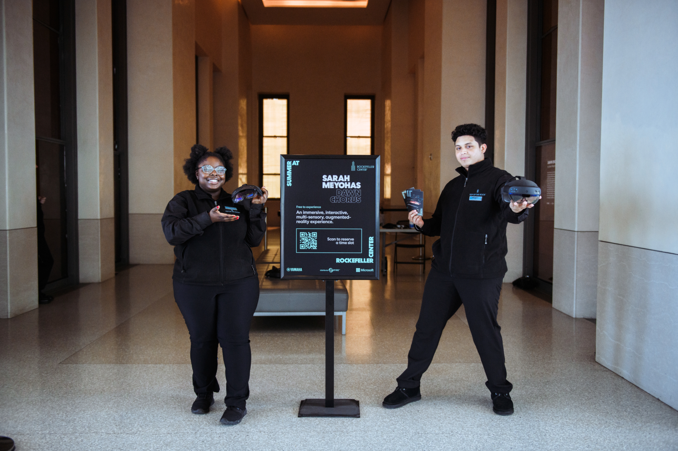 Dawn Chorus staff with AR headsets next to event sign
